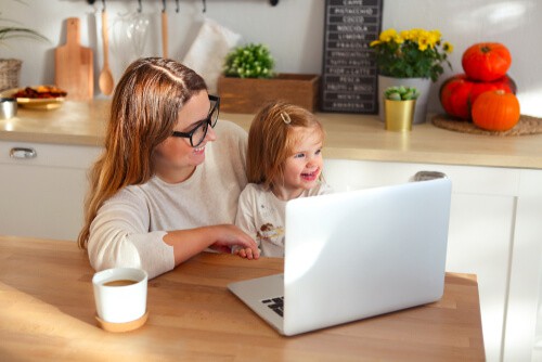 Mama arbeitet mit Kind im Homeoffice Business